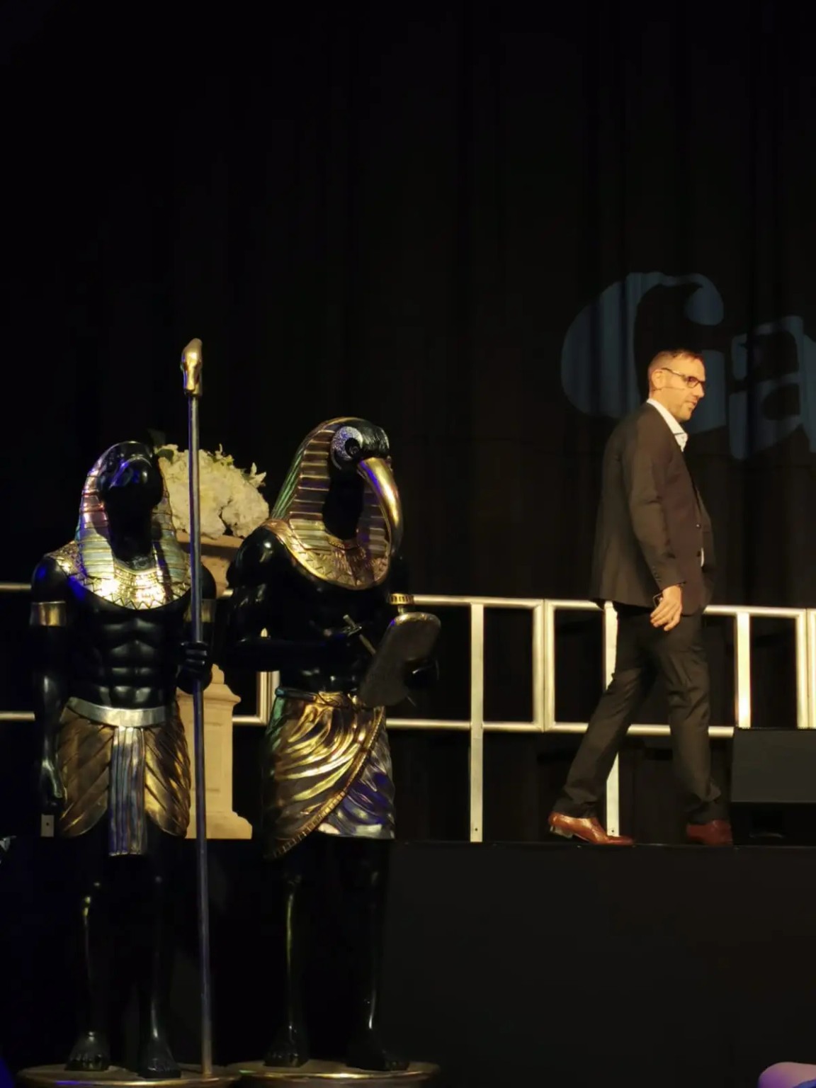 Jonny walking onstage beside Egyptian figures at a Gaia event