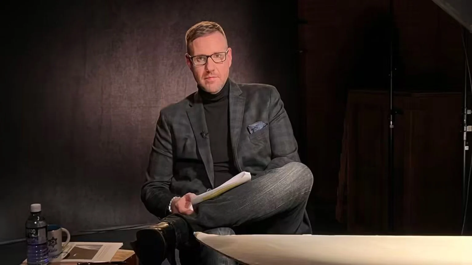 Jonny Enoch seated with his notes during a studio recording
